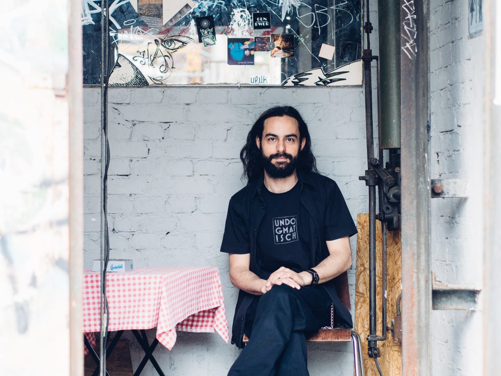 Daniele Antezza beside a sticker-covered window