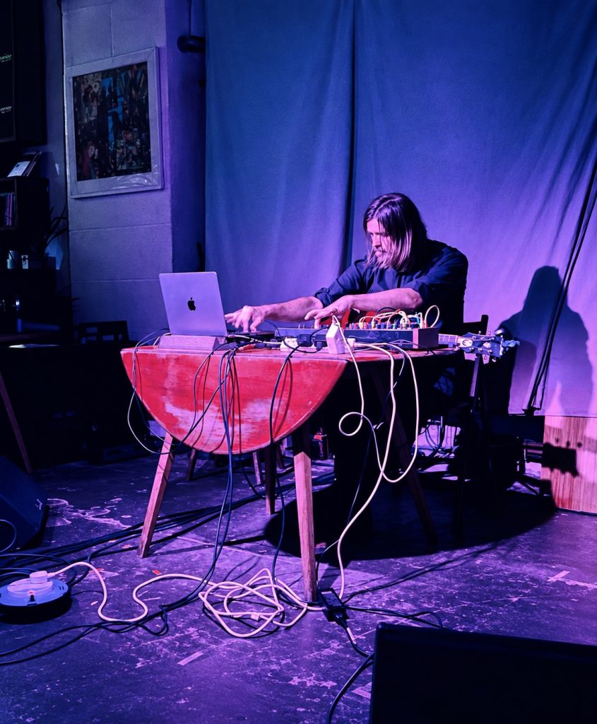 Simon Scott performing with guitar, electronics and a laptop