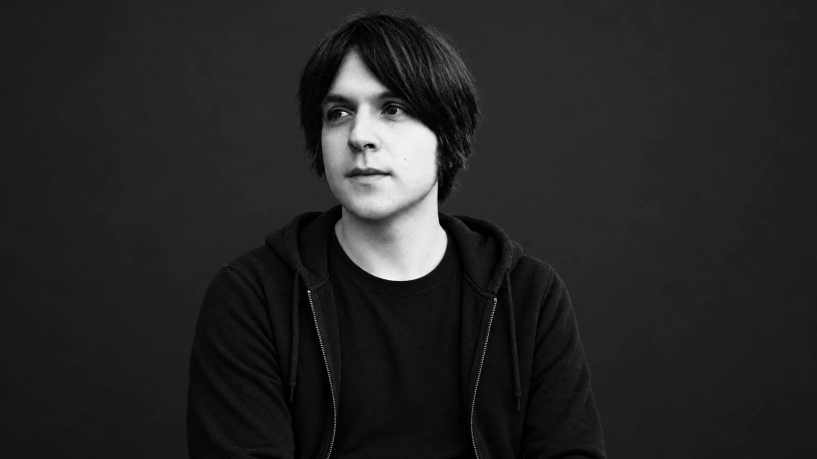 James Blackshaw in a black hooded sweatshirt — restored editorial portrait