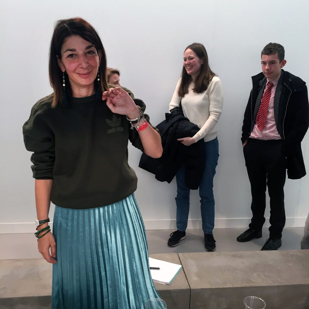 Mira Calix standing in a gallery at Frieze London, with other visitors behind her.