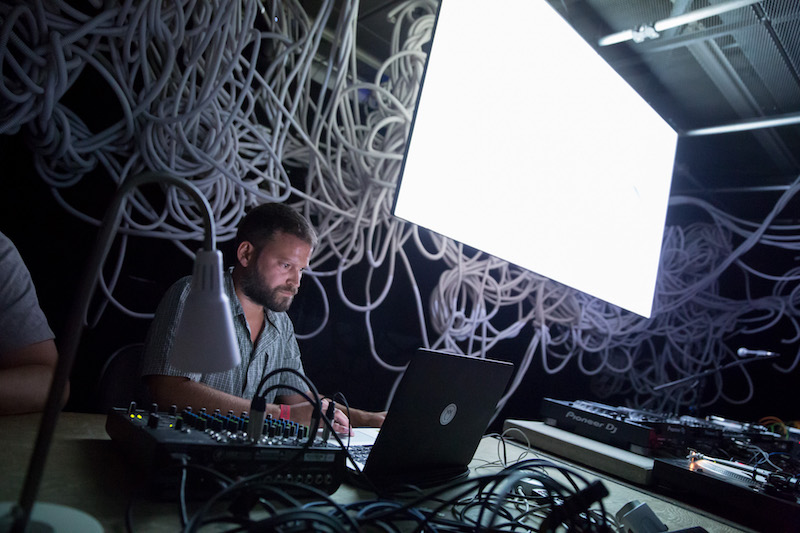 Gonçalo F Cardoso seated at a laptop and mixer during a performance.