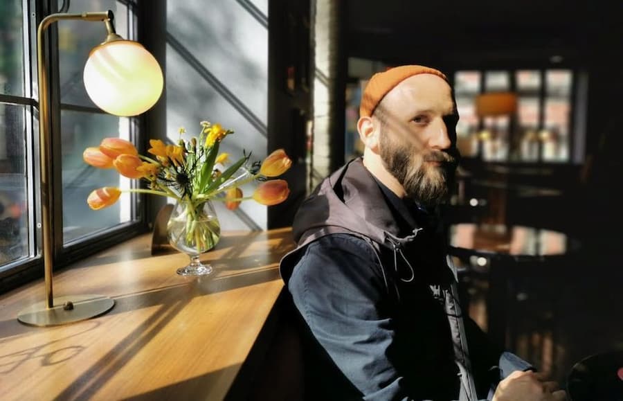Brandon Rosenbluth seated beside a window.